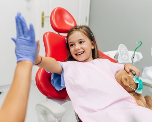 Cute little girl sitting on dental chair and having dental treatment.